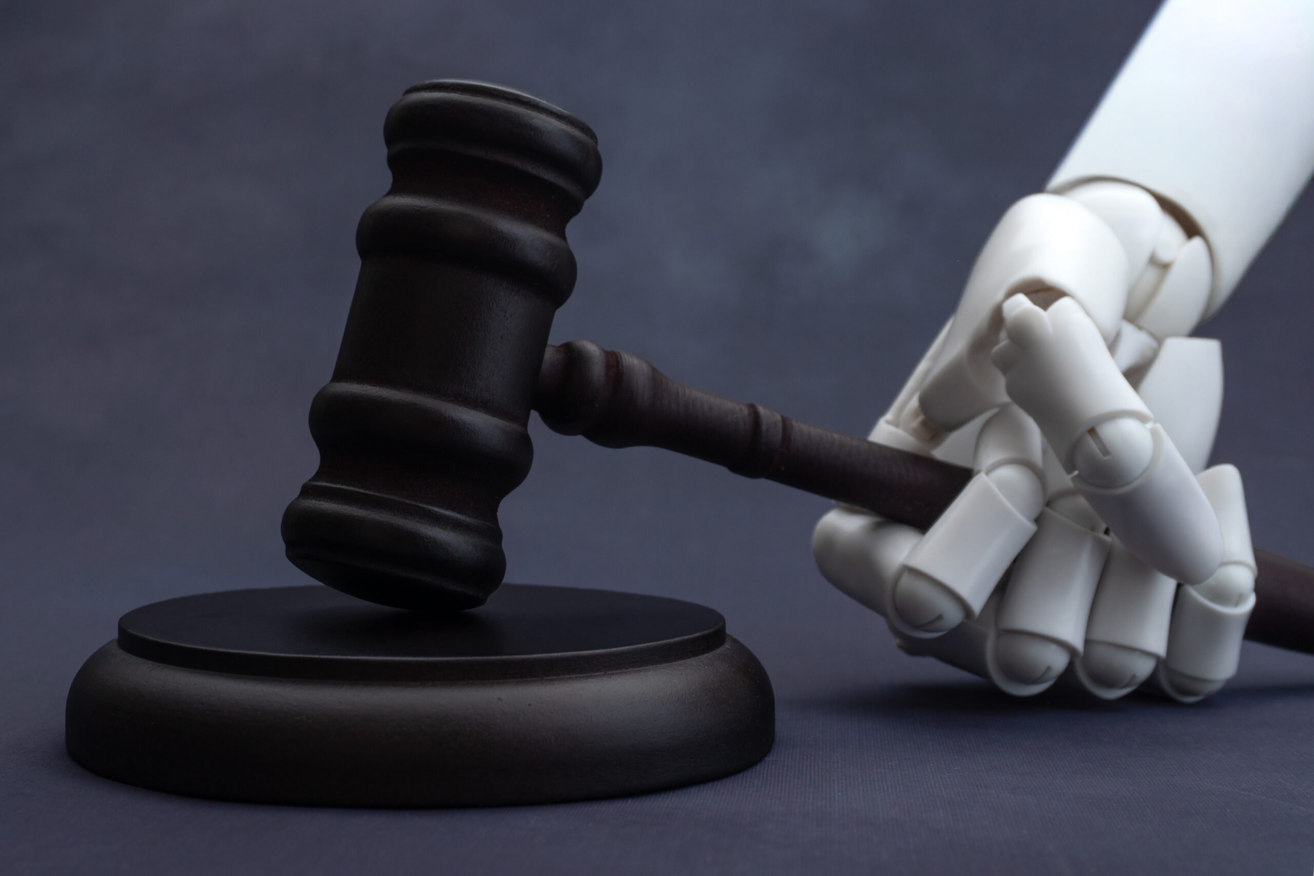 Robotic hand holding a judge's gavel, illustrating AI copyright law and legal questions surrounding generative content.